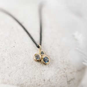 Blue sapphire cluster pendant handmade in gold on a blackened silver chain.