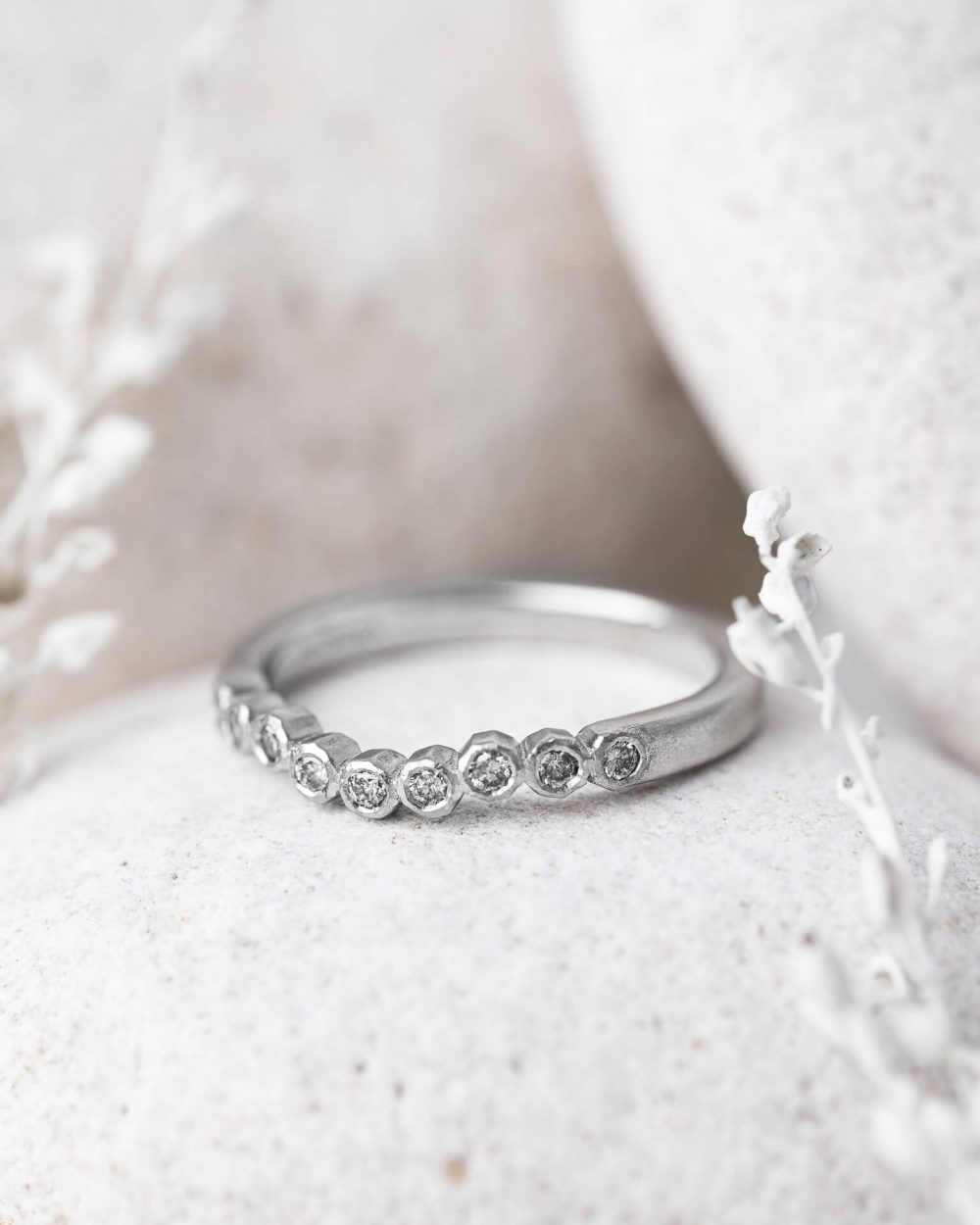 Geo Curved Salt And Pepper Diamond Ring, Handmade In Platinum. Pictured On A Pebble By Bristol Jewellery Designer Jacks Turner.