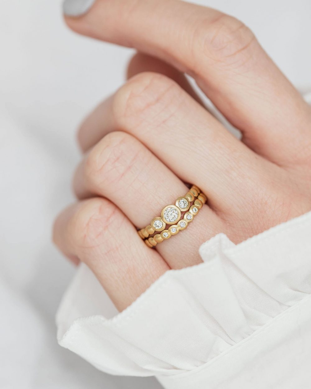Trio Diamond Engagement Ring In Yellow Gold, Pictured On Model Stacked Above Matching Curved Diamond Wedding Ring. Designed By Bristol Jeweller Jacks Turner.