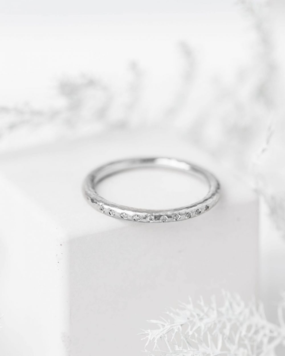 Hammered Diamond Wedding Ring Handmade In Platinum And Set With Ten Sparkle Diamonds, Pictured On Cube. Designed By Bristol Jeweller Jacks Turner.