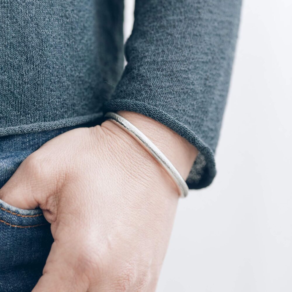 Huggie Silver Cuff Bracelet With Hammered Texture Finish On Model. Designed By Bristol Contemporary Jeweller Jacks Turner.